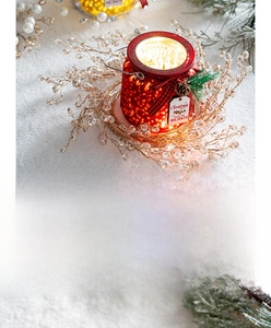 Close-up of a red festive Christmas lantern with a beaded wreath on snowy white surface