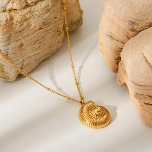 Detail shot of a gold-plated nautilus shell pendant on a beaded stainless steel chain