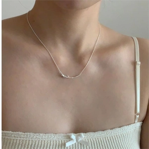 Close-up of minimalist S925 silver necklace with a side bow pendant on a model