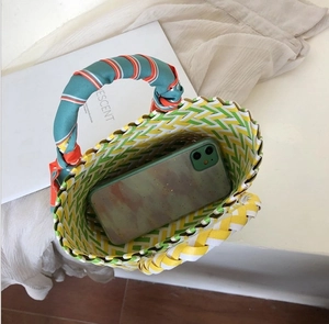 Vue de dessus d'un sac panier tressé avec rayures colorées et anse en foulard de soie