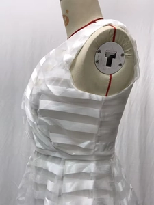 Dettaglio del vestito bianco smanicato con strati di tulle e trama a pieghe