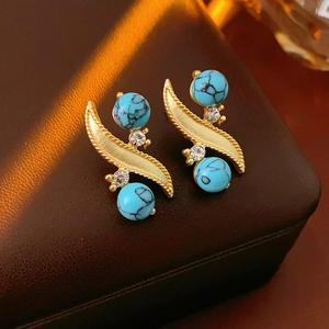 Detailed view of vintage gold textured earrings with turquoise beads and small crystals
