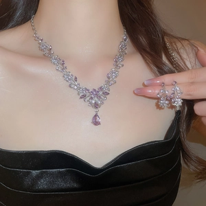 Detail of purple gem flower necklace and drop earrings set on model in black dress