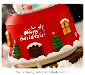 Macro shot of red Christmas music box base with 3D snowy tree and Merry Christmas text
