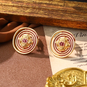 Detail of vintage gold spiral stud earrings with red enamel on a retro paper background