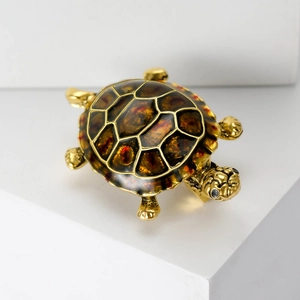 Detailed macro view of a vintage golden turtle brooch with amber enamel and gemstone eyes