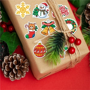 Close-up of holographic Christmas stickers on a kraft gift box with festive decorations
