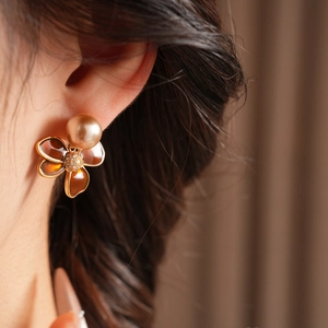 Détail de boucle d'oreille fleur vintage avec émail marron et perles sur mannequin