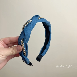 Detail view of blue denim knotted headband with decorative gold chain and black lining
