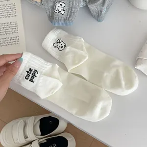 Detail of cute puppy embroidery and typography on white knitted cotton ankle socks