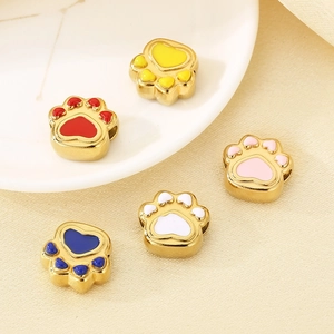 Close-up of colorful enamel cat paw beads in gold plating on a ceramic tray