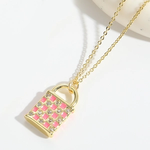 Close-up of golden envelope pendant necklace with pink enamel grid and crystal detail