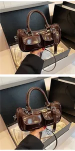 Detail view of dark brown patent leather bowling bag with silver zippers and pockets