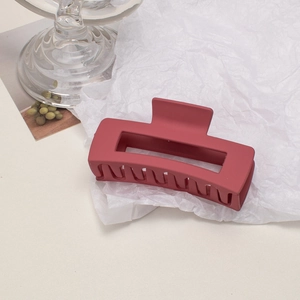 Detail of matte dark red large hair claw clip on white crinkle paper background