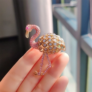 Elegant flamingo brooch featuring pink and blue crystals set in a golden metal base