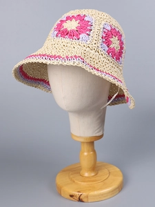 Detail of handmade crochet straw hat with colorful floral patterns and scalloped edges