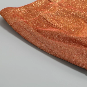 Vista macro del tessuto a maglia glitter arancione con cuciture dettagliate del set
