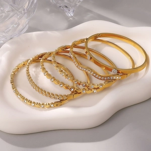 Set di 6 lussuosi braccialetti placcati oro con strass su un piatto di ceramica bianco