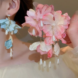 Detail of pink and blue fabric flower earrings with long pearl tassels shown on model
