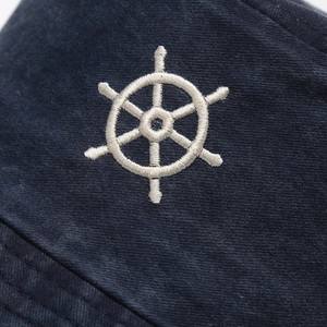 Close-up of white helm embroidery on navy blue washed cotton bucket hat fabric