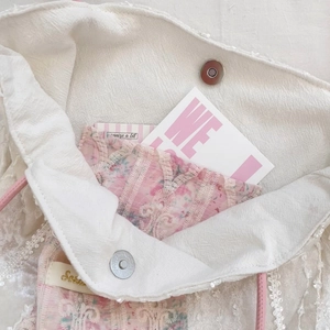 Detail view of white canvas tote featuring pink floral lining and silver magnetic buckle