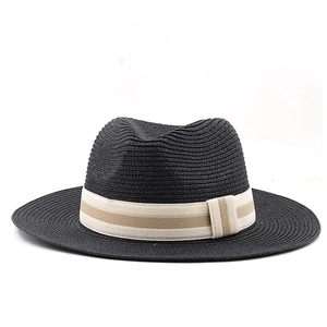 Detail of black straw fedora hat featuring a beige striped ribbon and woven texture
