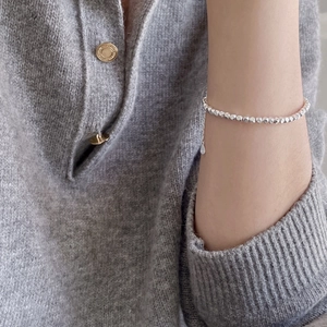 Minimalist S925 sterling silver faceted bead bracelet on wrist with a gray knit background