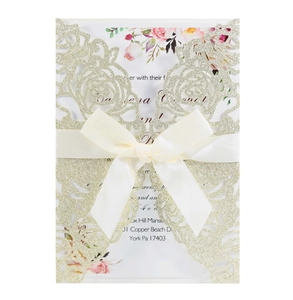 Detail of laser-cut rose hollow invitation with gold glitter and cream ribbon bow