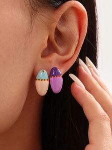 Detail of 18k gold plated enamel eggshell stud earrings worn by a model in close-up view