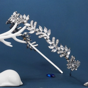 Close-up of silver leaf headband with clear crystals on a textured blue background