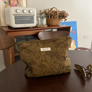 Close-up of brown floral embroidery and simple wish label on vintage cosmetic bag