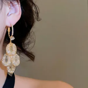 Elegant gold leaf tassel earrings with zircon pave on model in soft warm lighting