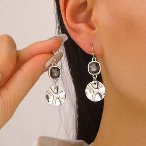 Close-up of vintage silver earrings with grey resin stone and embossed metal discs