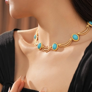 Macro detail of vintage gold necklace featuring oval turquoise stones and textured metal