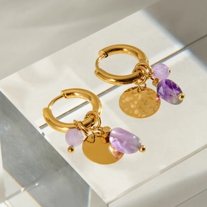 Boucles d'oreilles martelées en or avec pierres naturelles mauves sur un support