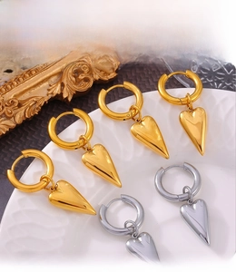 Macro shot of PVD electroplated gold and silver heart earrings on a white plate