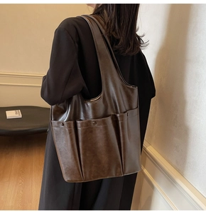 Side view of dark brown large tote bag with three pockets on model in a cozy interior