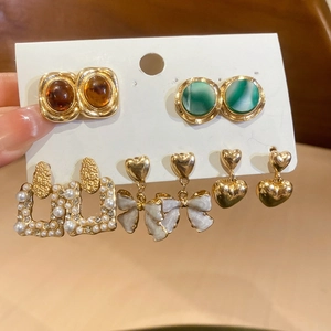 Detail view of retro french style floral pearl earrings set in gold and resin colors