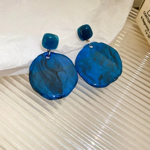 Detailed view of irregular round resin earrings with dark blue ink texture on glass