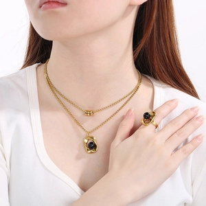 Close-up of gold double-layer necklace and matching ring with elegant black pearl accents