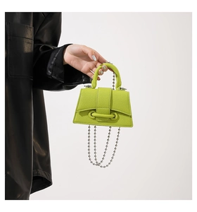 Close-up of neon green leather mini handbag with silver ball chain and textured finish