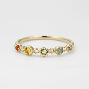 Macro view of five colorful gemstones set in a textured gold-plated silver band