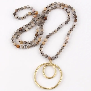 Detail of golden double-loop geometric pendant with grey earthy gemstone beads