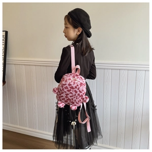 Detailed side view of pink leopard print plush backpack worn by a child on white wood