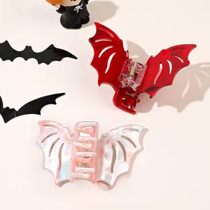 Macro detail of bat-shaped hair claws in red and pink marble acetate for Halloween