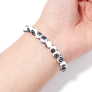 Detail view of white Millefiori glass evil eye beads strung on a minimalist bracelet