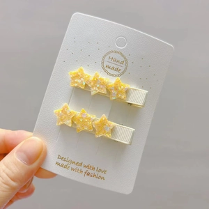 Close-up of yellow glitter star hair clips on a white card for girls hair styling