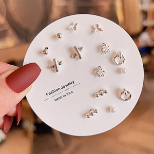 Macro shot of silver stud earring set with butterfly, flower and pearl designs on card