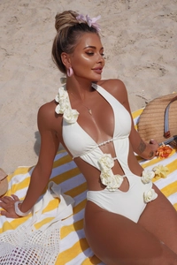 Close-up of white monokini with 3D floral details and pearl beads on beach towel