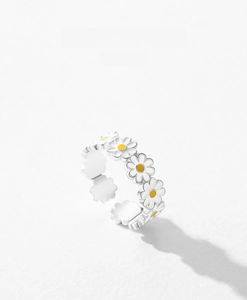 Detailed macro view of silver open ring with white enamel daisies and yellow centers